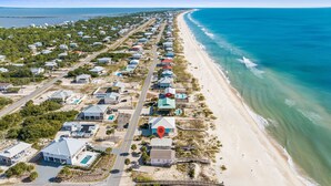 An aerial view of a coastal residential area with houses, a beach, and a clear blue ocean. - Sunflower 3, Pet friendly, Beachfront. (Eastpoint)
