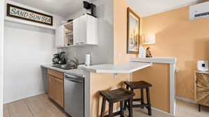 A compact kitchen with a sink, cabinets, and a countertop. A sign reads "SAND SUN SEA." - Sunflower 3, Pet friendly, Beachfront. (Eastpoint)