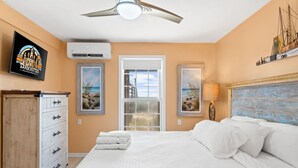 A bedroom with a bed, a dresser, a ceiling fan, and a TV displaying a logo. - Sunflower 3, Pet friendly, Beachfront. (Eastpoint)