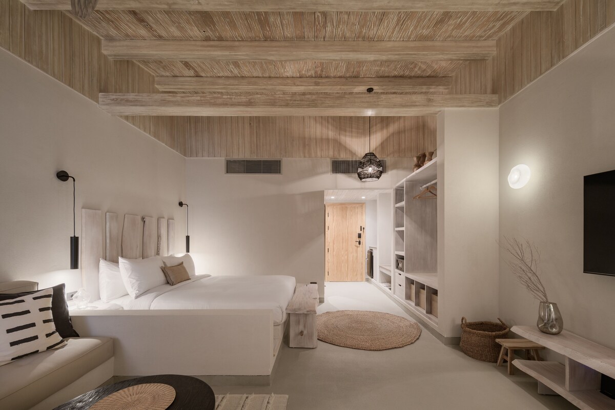 Een moderne slaapkamer met een groot bed, een nachtkastje, een hanglamp en inbouwkasten.