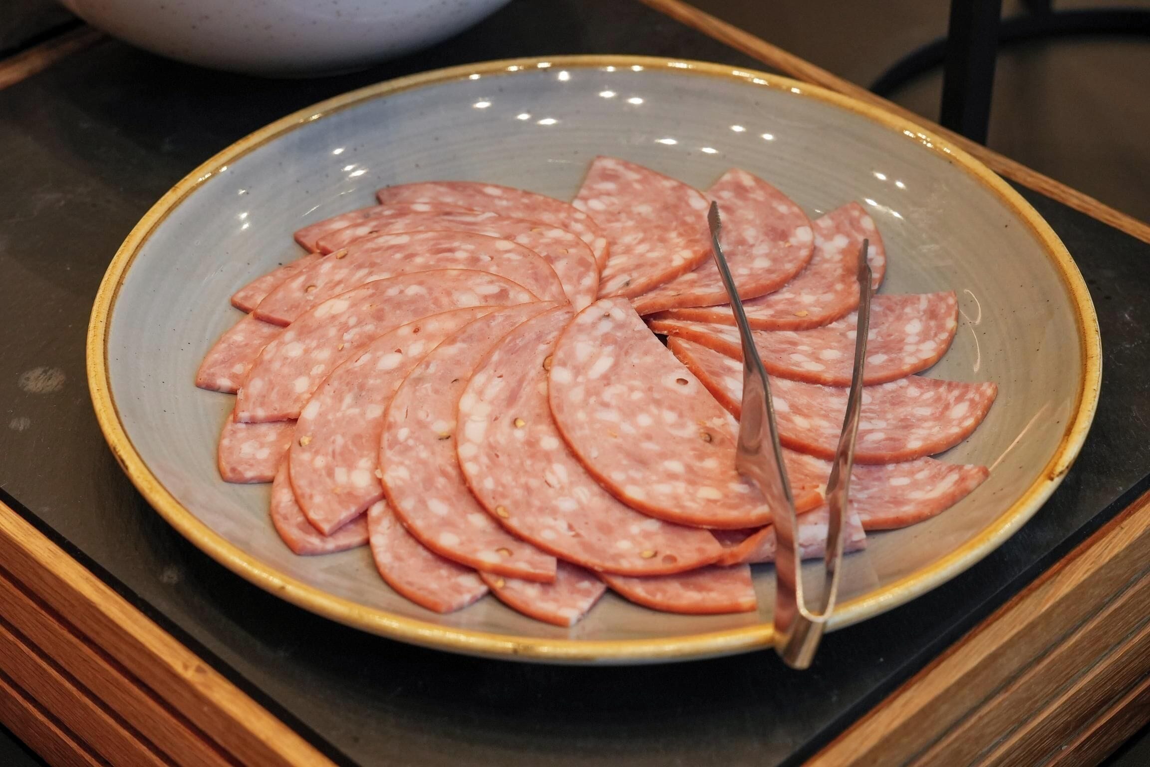 A plate of sliced salami on a ceramic plate.