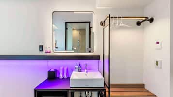 A modern bathroom with a white sink, a mirror, and a shower area.