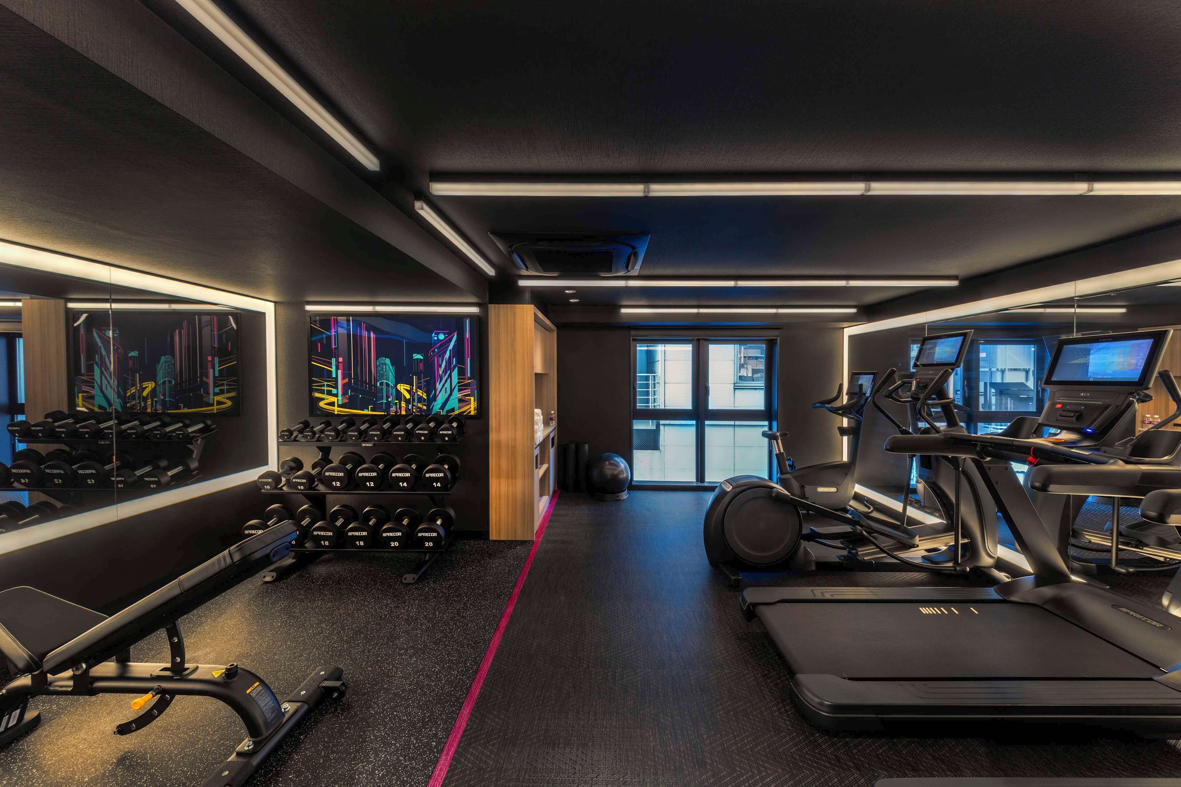Un gimnasio moderno con cintas de correr, elípticas y equipo de levantamiento de pesas.