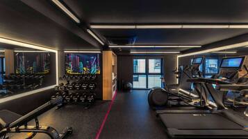 Un gimnasio moderno con cintas de correr, elípticas y equipo de levantamiento de pesas.