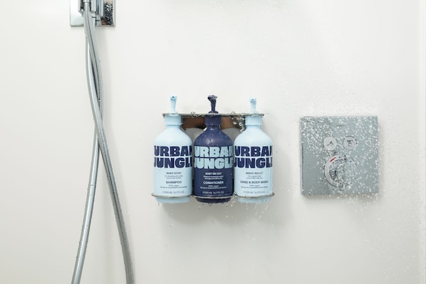 A shower with three bottles of Urban Jungle products: shampoo, conditioner, and hand & body wash. - YOTEL Tokyo Ginza (Tokyo)