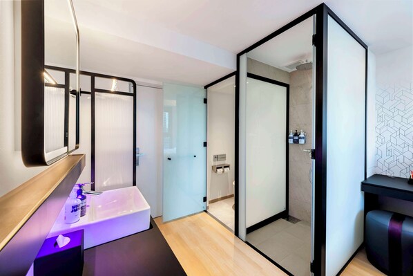 Un baño moderno con mampara de vidrio, un lavabo blanco y un espejo.