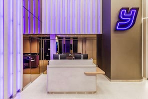 A reception area with a modern design, featuring a reception desk, seating area, and a neon sign. - YOTEL Tokyo Ginza (Tokyo)