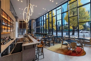 Un espace bar moderne doté d’un comptoir, de tabourets et de sièges. De grandes fenêtres offrent une vue sur l’extérieur.