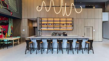 A modern bar area with a central island, bar stools, and a variety of bottles.