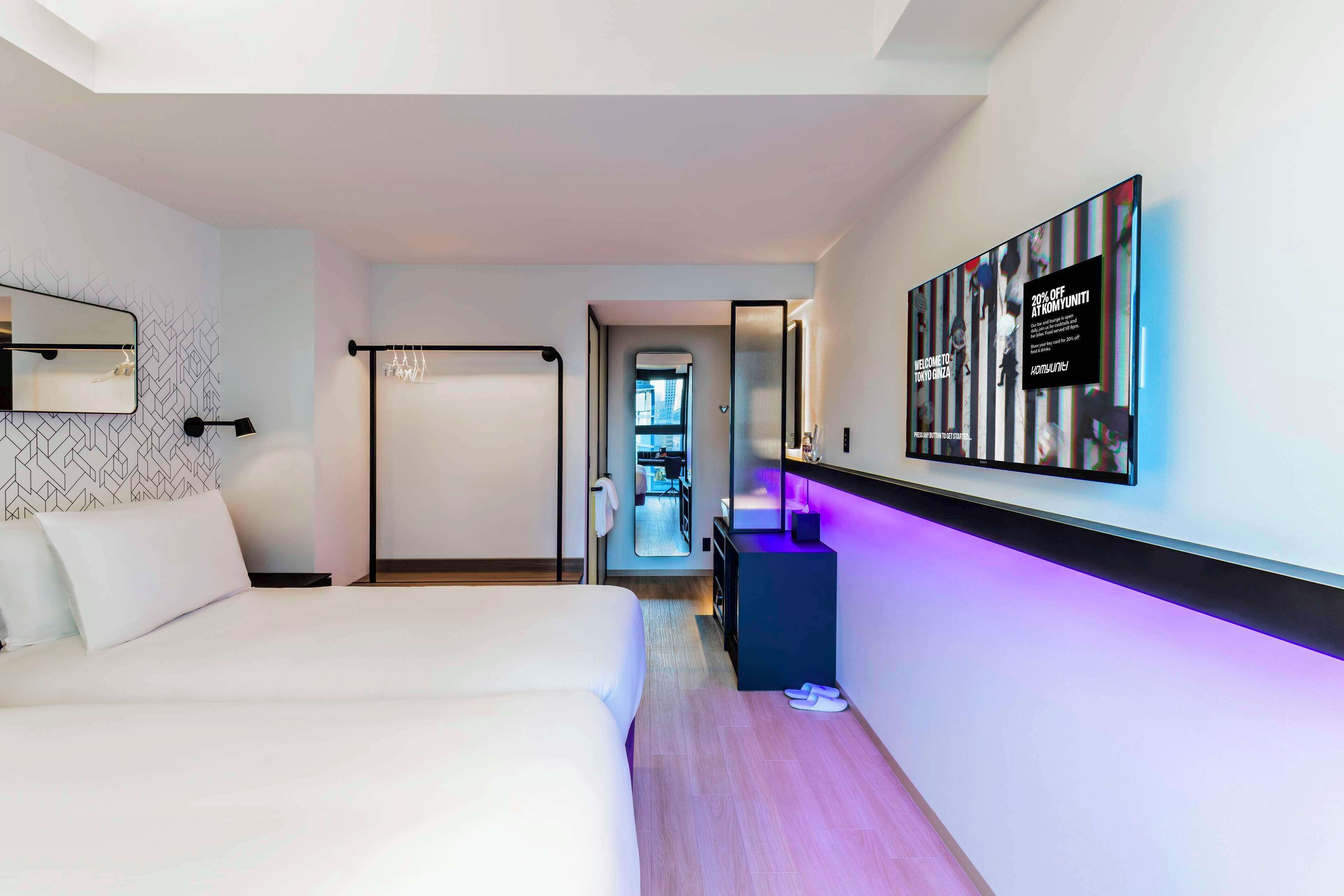 A modern hotel room with a large bed, a desk, and a wall-mounted TV.