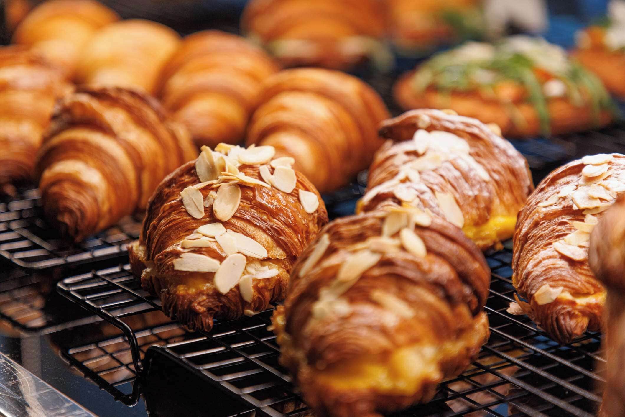A bakery display with croissants and pastries on a wire rack.