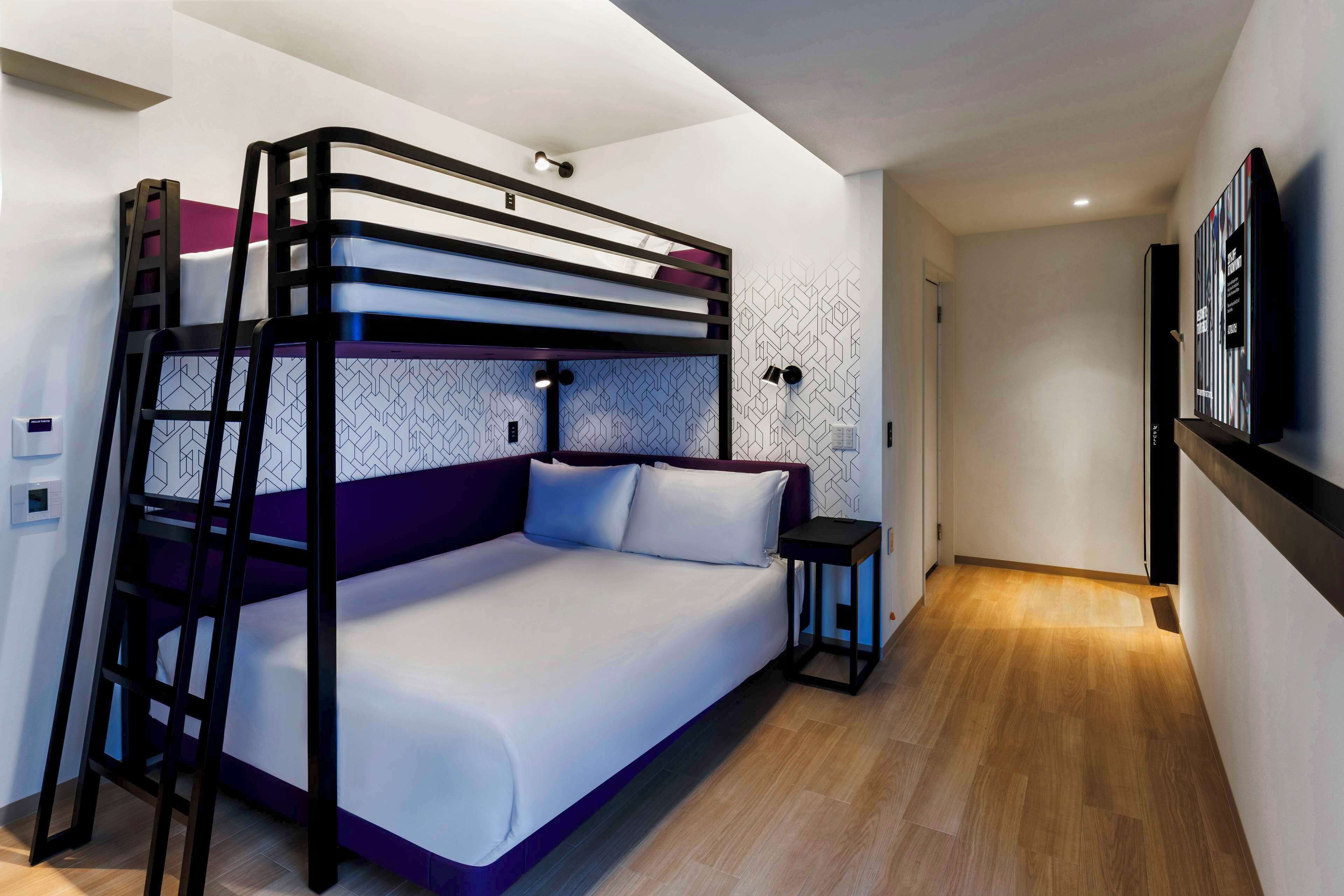 A bunk bed with a ladder, a small table, and a TV on the wall.