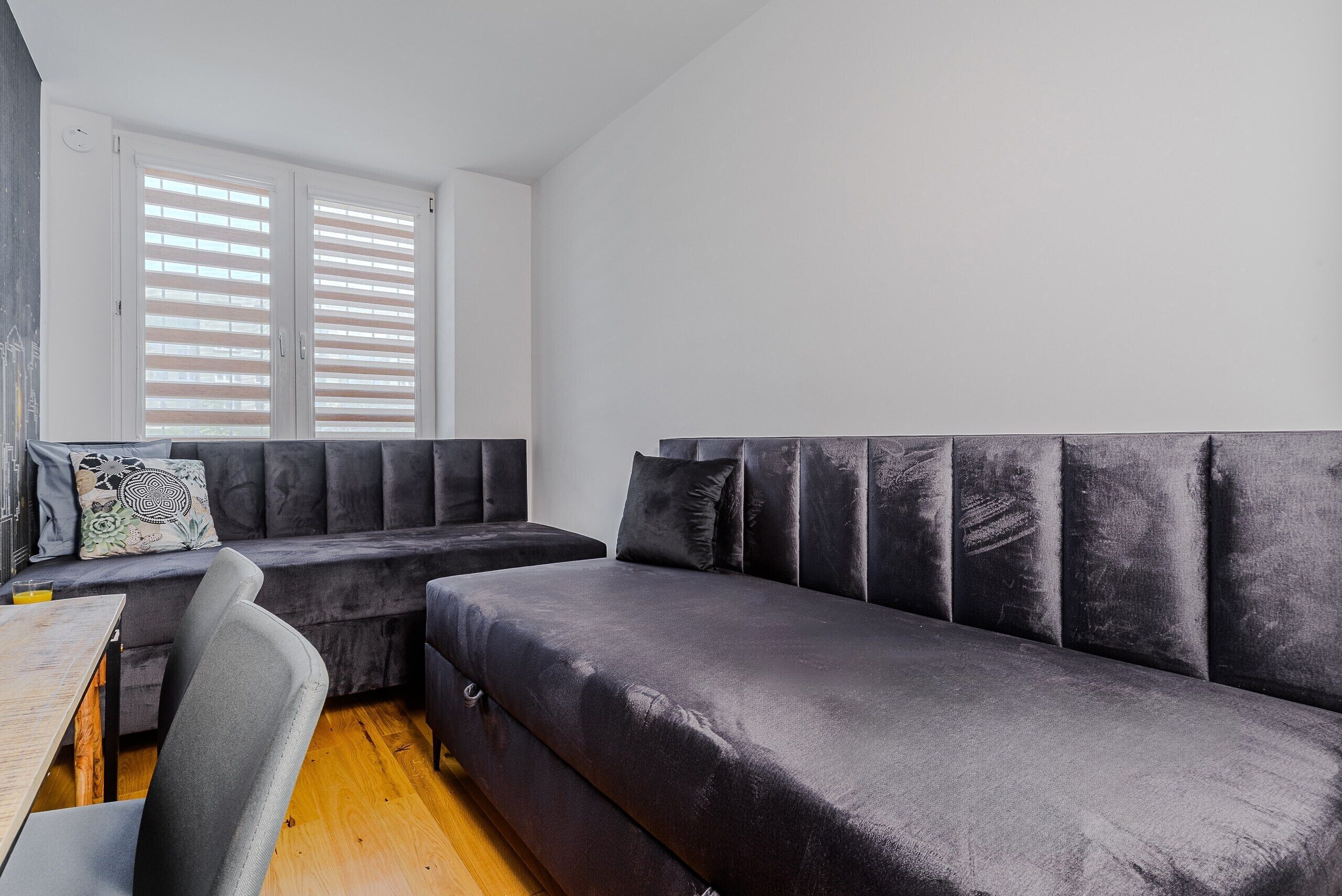 A modern room with a large dark sofa, a small table, and a bench.