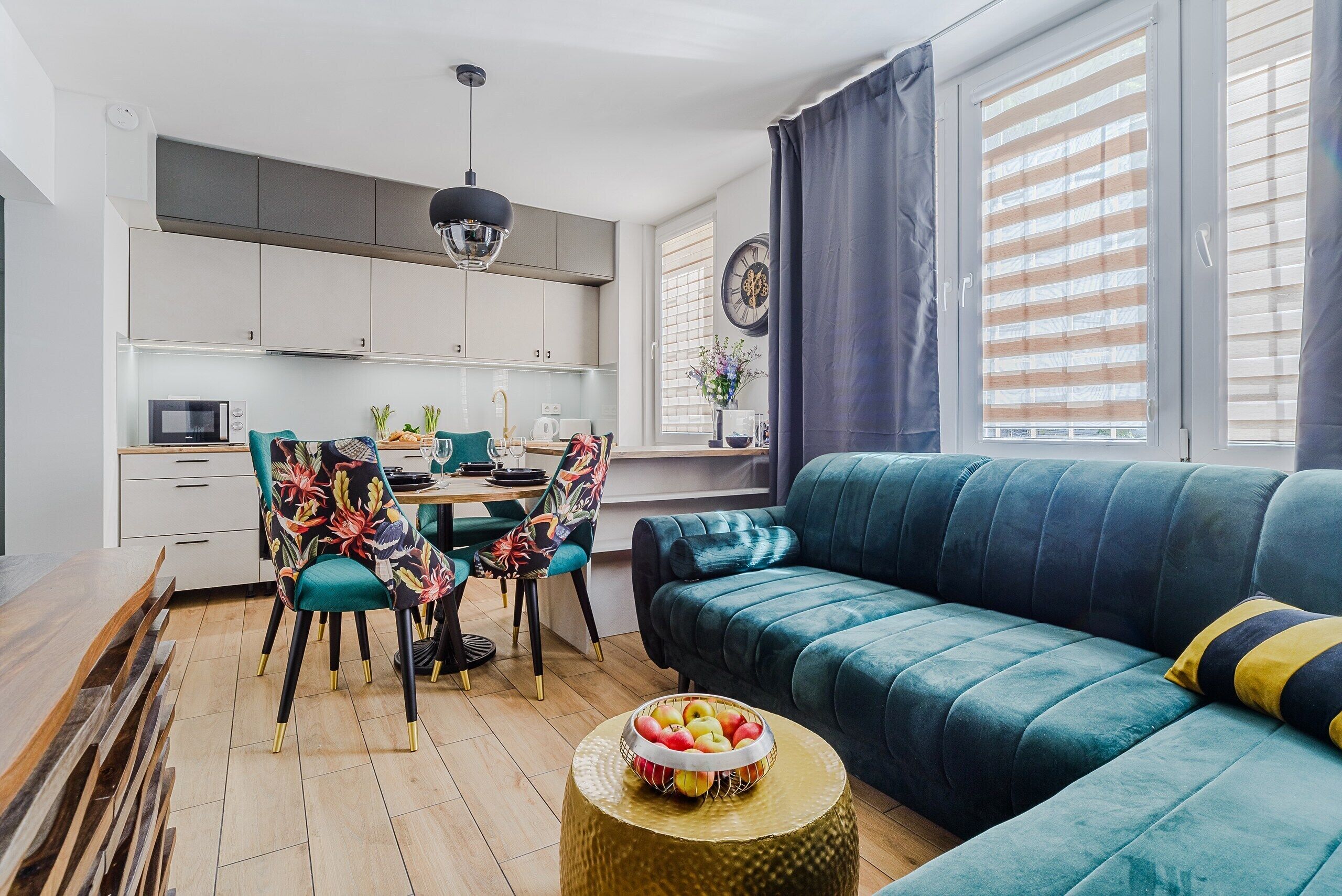 A modern living room with a sofa, chairs, a dining table, and a kitchen in the background.
