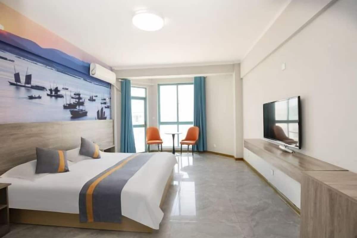 Ein Hotelzimmer mit Bett, Fernseher, Schreibtisch und einem Bild an der Wand.