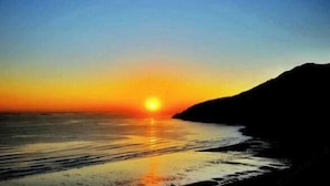 A sunset over a body of water with a silhouette of a hill. - Lianyungang Liandao Yanyangtian Holiday Center (Lianyungang)