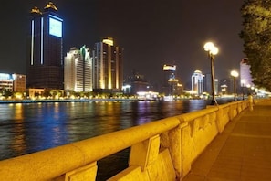 A nighttime cityscape with illuminated buildings along a waterfront. - Baiyuan Hotel (Baogang Avenue Subway Station) (Guangzhou)