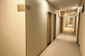 A hotel hallway with doors on both sides, a carpeted floor, and a sign indicating room numbers. - Baiyuan Hotel (Baogang Avenue Subway Station) (Guangzhou)