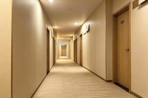 A hotel corridor with doors on both sides, carpeted floor, and overhead lighting. - Baiyuan Hotel (Baogang Avenue Subway Station) (Guangzhou)