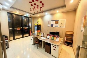 A reception area with a desk, chairs, a plant, and a glass door leading to another room. - Baiyuan Hotel (Baogang Avenue Subway Station) (Guangzhou)