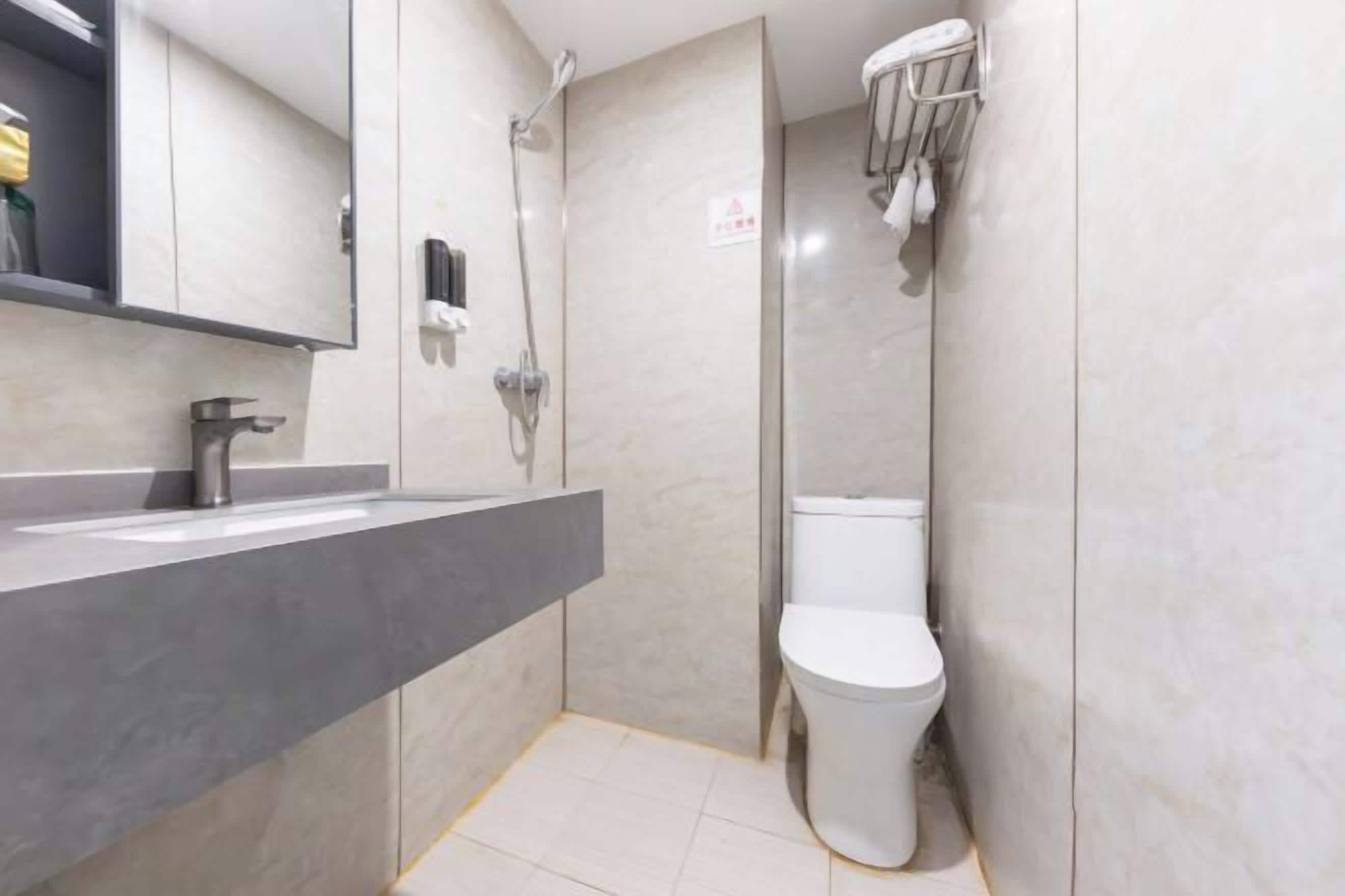 A modern bathroom with a grey sink, a toilet, and a shower.