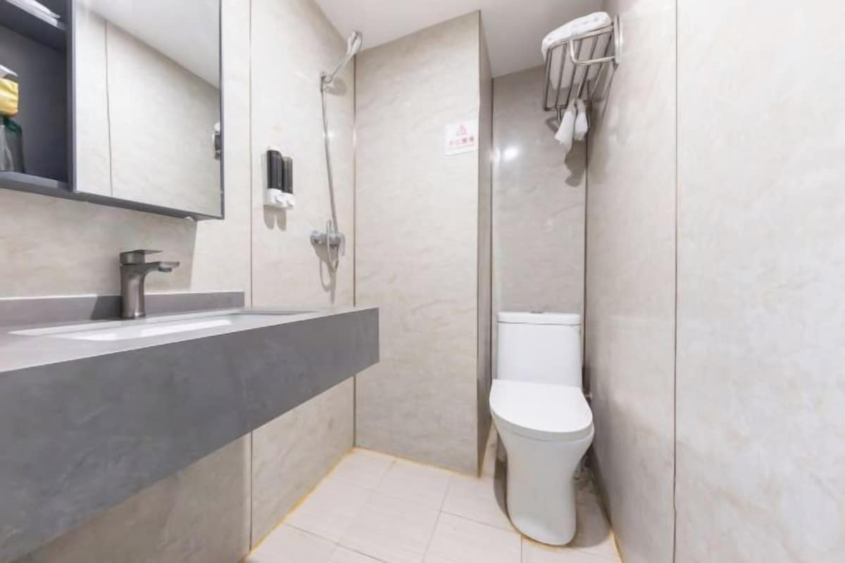 Un baño moderno con un lavamanos gris, un inodoro y una ducha.