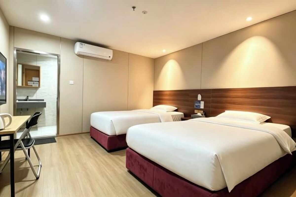 Quarto de hotel com duas camas, uma escrivaninha e um espelho.