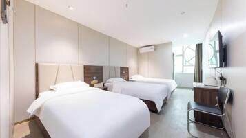 A hotel room with two beds, a desk, a chair, and a TV.