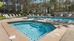 Ein rechteckiger Pool mit Sprungbrett, umgeben von Liegestühlen und einer Steinmauer.