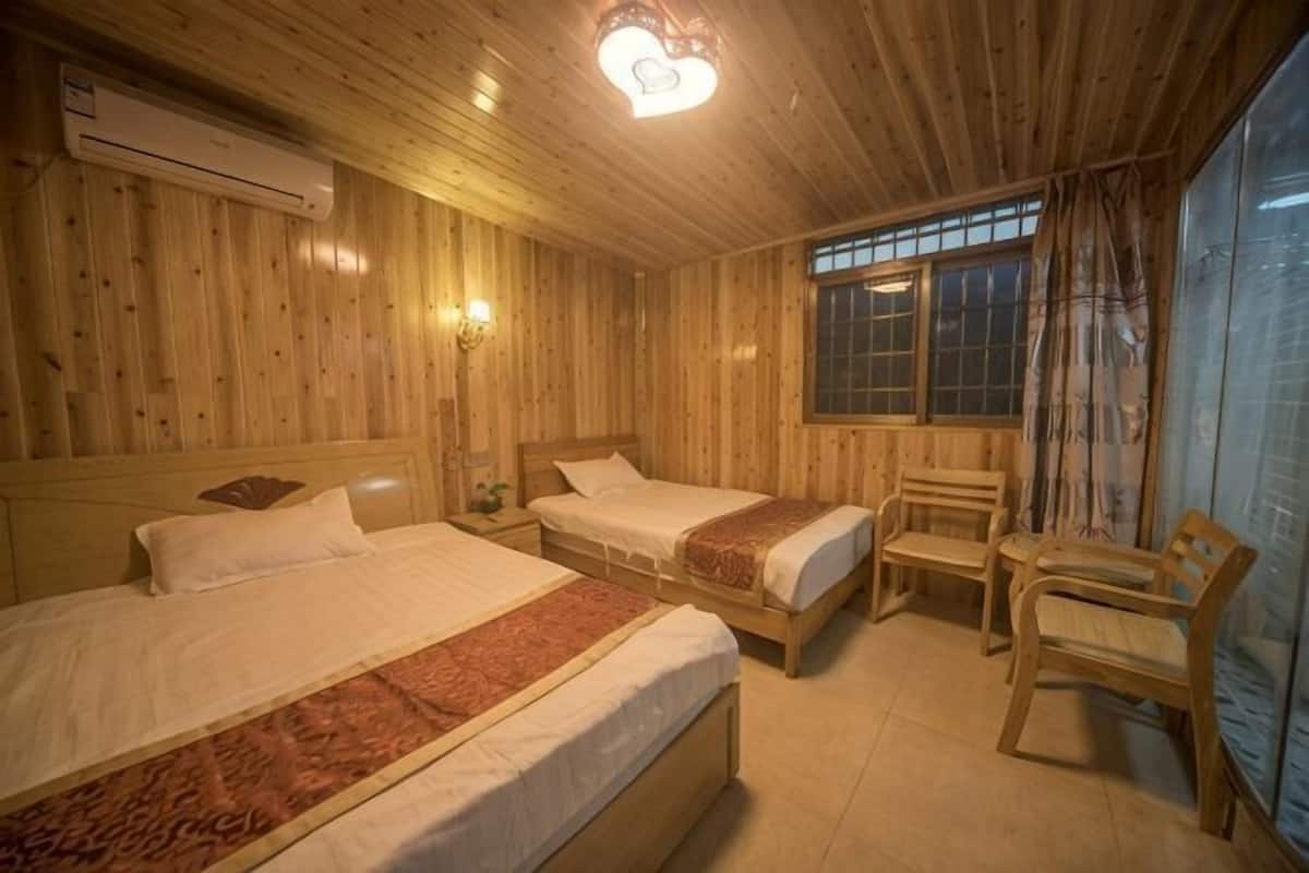 A room with two beds, a wooden ceiling, a window with curtains, and a chair.