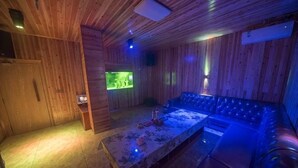 Un intérieur en bois avec une longue table, des sièges rembourrés et un téléviseur.
