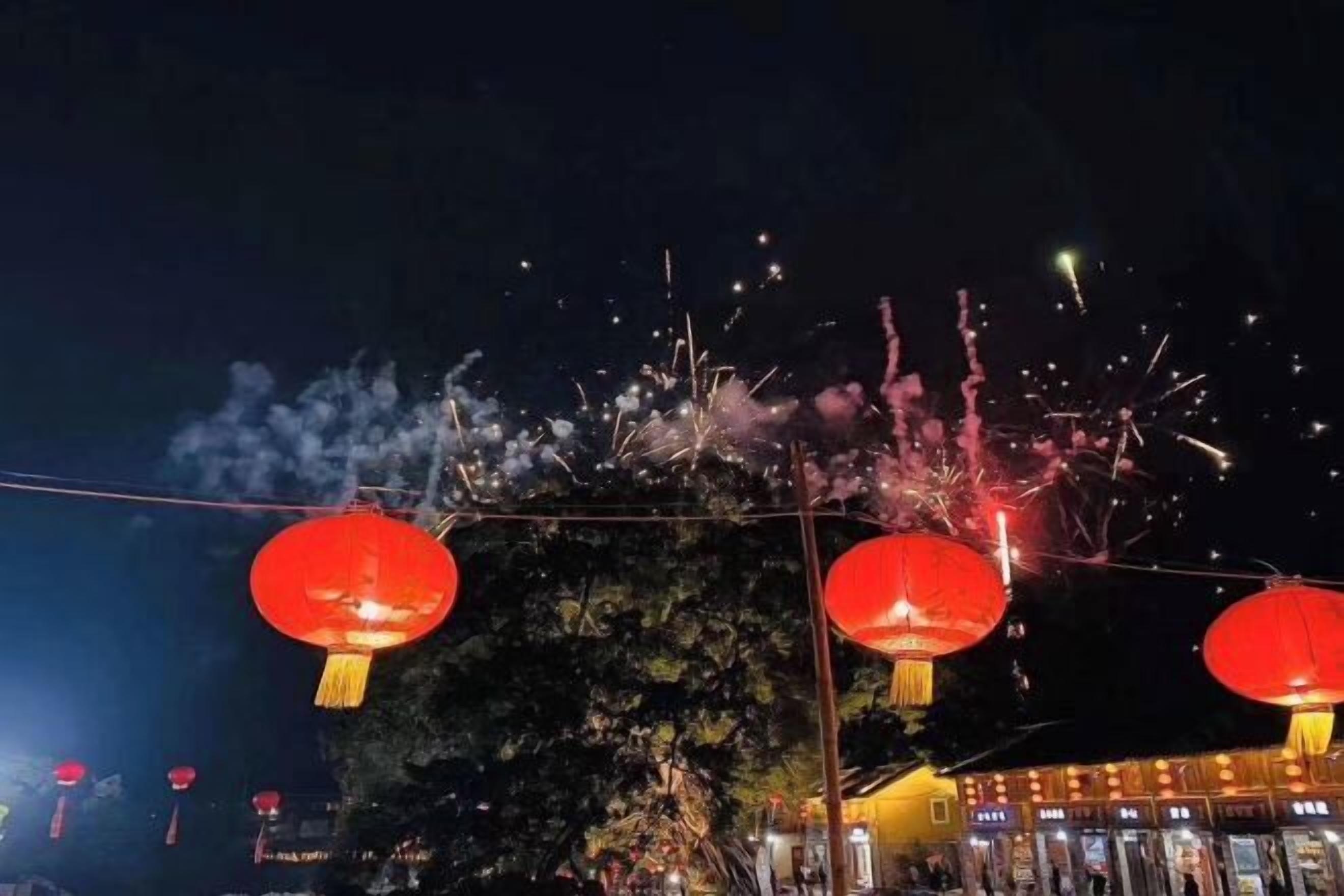 A night scene with red lanterns and fireworks.