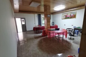 Una habitación con techo de madera, suelo de baldosas, una mesa redonda con sillas y una puerta al fondo.