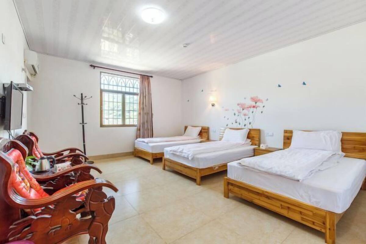 A hotel room with two wooden beds, a desk with a chair, a TV, and a window with curtains.