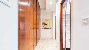 A hallway with wooden cabinets, a tiled floor, and a painting on the wall.