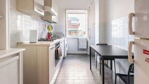 A compact kitchen with a washing machine, a dining table, and a refrigerator.