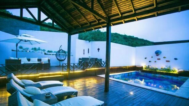 A rooftop pool area with lounge chairs, a table, and a view of the surrounding landscape. - LongXianJu Hotel (Shengsi)