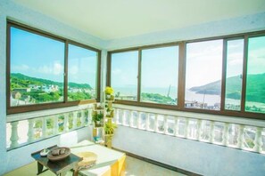 A balcony with large windows overlooking a coastal landscape. - LongXianJu Hotel (Shengsi)