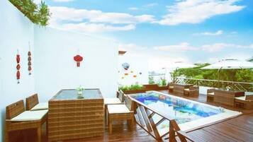 A wooden deck with a pool, wicker furniture, and a white wall with decorations.