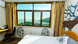 A hotel room with a large window, a bed, a desk, and a chair. - LongXianJu Hotel (Shengsi)