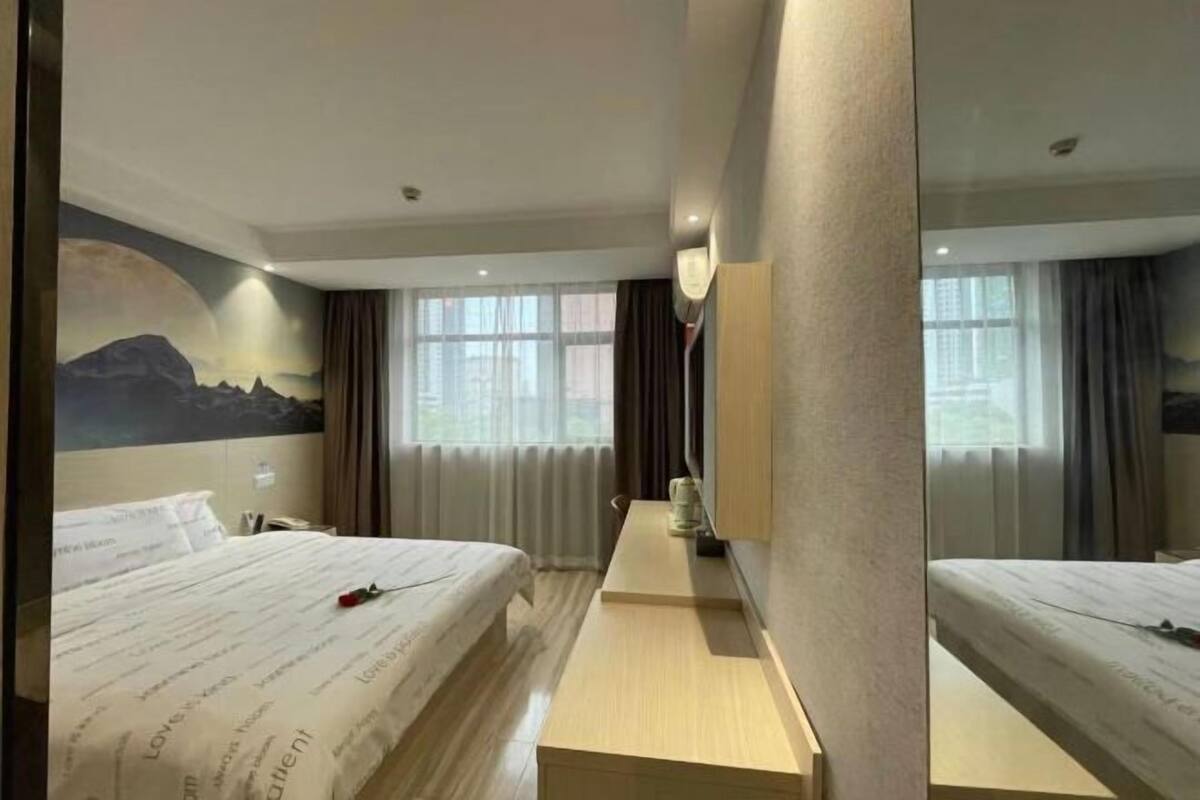 A hotel room with a bed, a desk, and a large mirror.