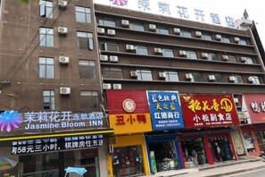 A multi-story building with various commercial establishments on the ground floor, including a hotel and several shops. - Jasmine Bloom INN Chain Hotel (Yidu Chengxiang Road) (Yidu)