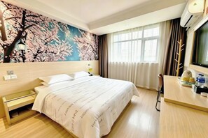 A hotel room with a bed, a desk, a chair, a window with curtains, and a wall with a cherry blossom mural. - Jasmine Bloom INN Chain Hotel (Yidu Chengxiang Road) (Yidu)