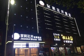 A building with multiple illuminated signs, including 'Jasmine Bloom INN' and 'Jasmine Bloom Hotel'. - Jasmine Bloom INN Chain Hotel (Yidu Chengxiang Road) (Yidu)