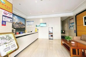 A hotel reception area with a reception desk, a television screen, and a seating area with a sofa and a coffee table. - Jasmine Bloom INN Chain Hotel (Yidu Chengxiang Road) (Yidu)
