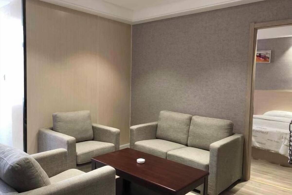 A hotel room with a sofa set, a small table, and a bed.
