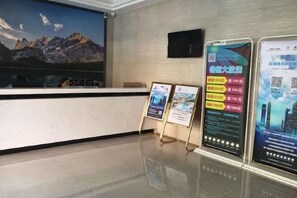 A reception area with a counter, a mounted television, and informational posters. - Jasmine Bloom INN Chain Hotel (Yidu Chengxiang Road) (Yidu)