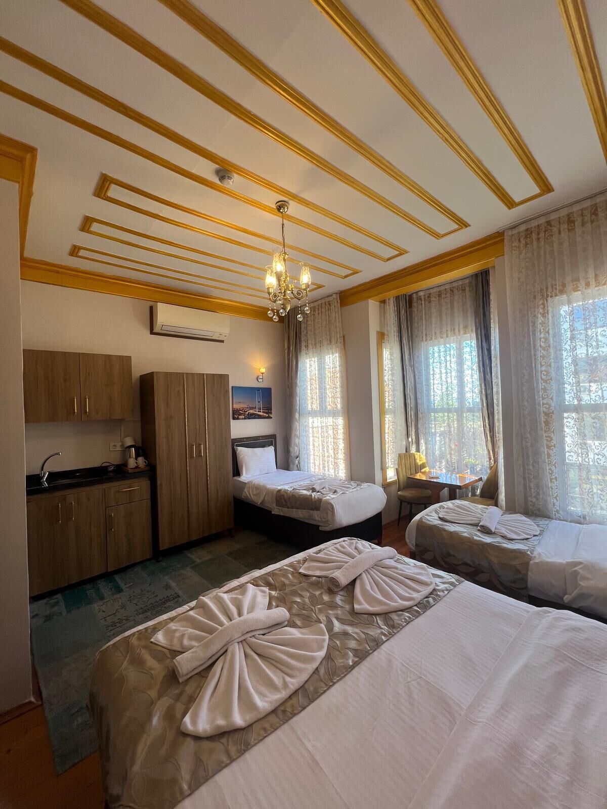 Une chambre d’hôtel avec deux lits, une kitchenette et un lustre.