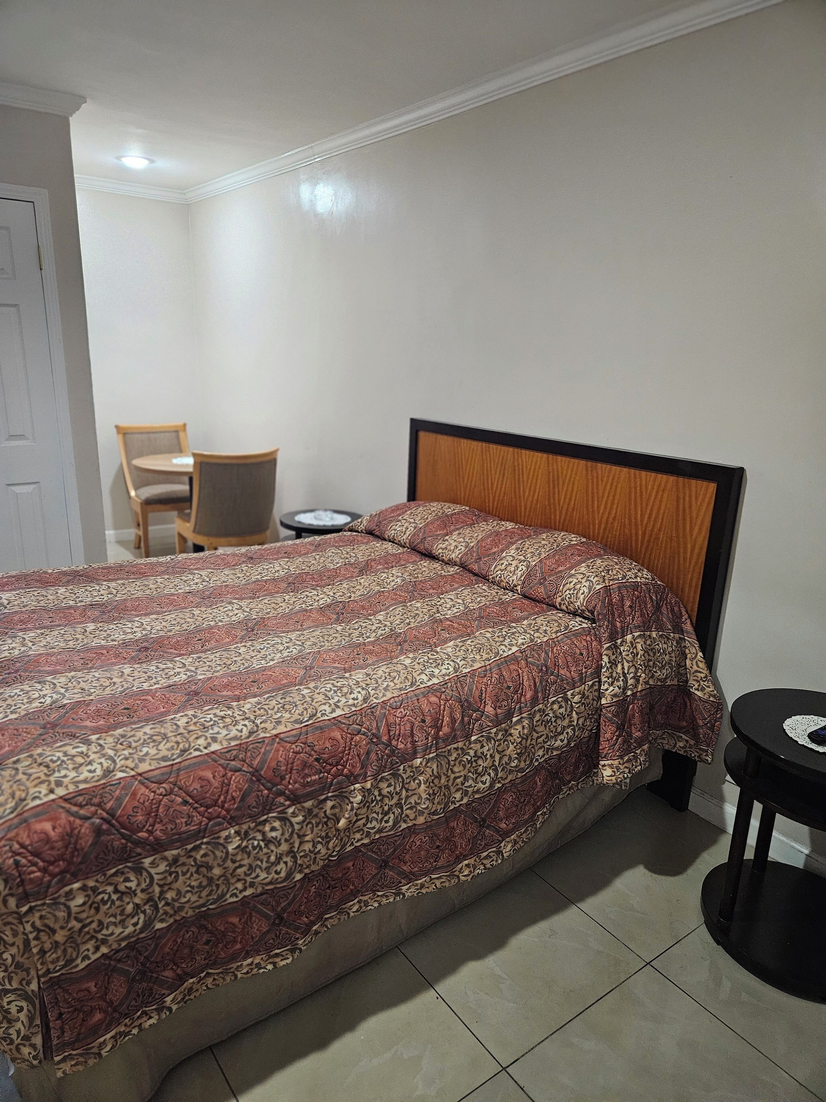 Una camera da letto con un letto grande, una testiera in legno, un tavolino rotondo e una sedia.