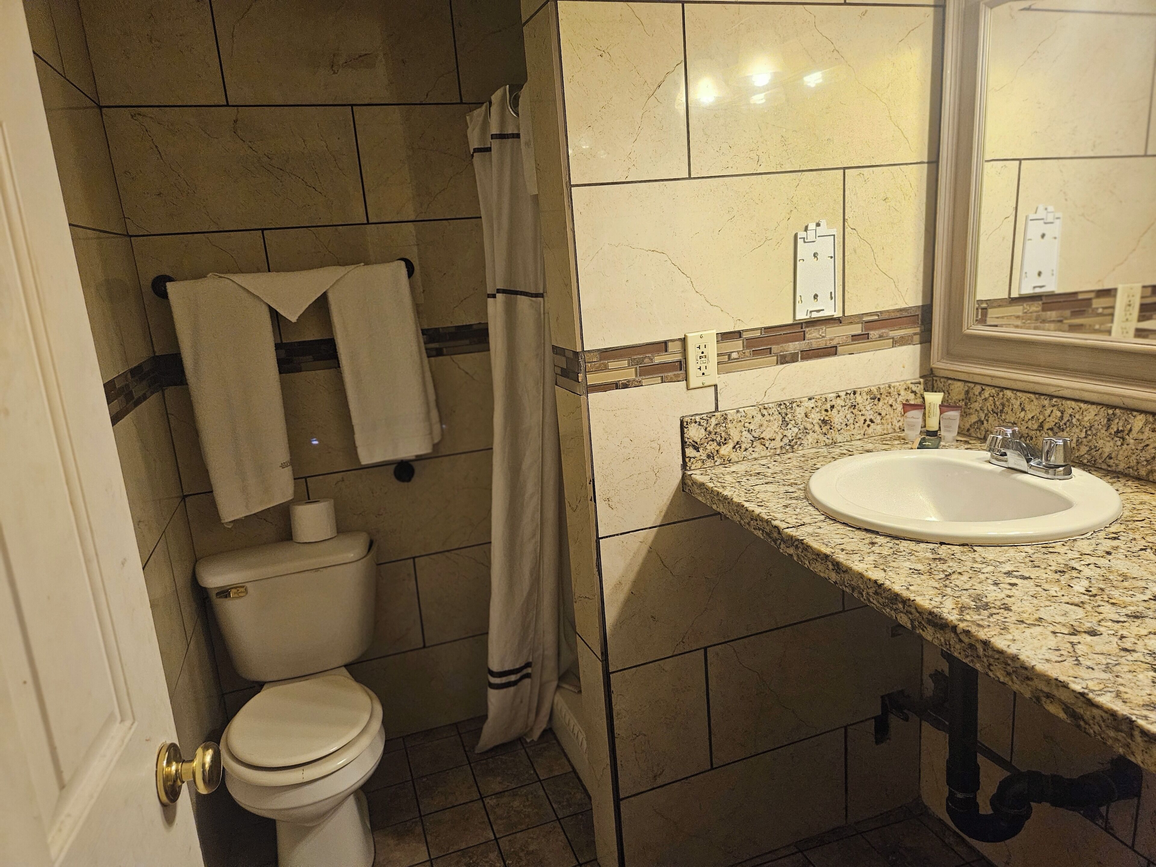 Un baño con inodoro, lavamanos y cortina de ducha.